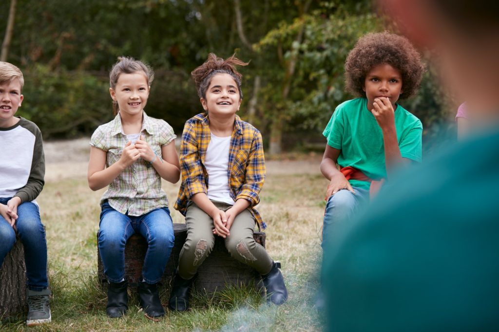 Children On Outdoor Activity Camping Trip Sit Around Camp Fire Together