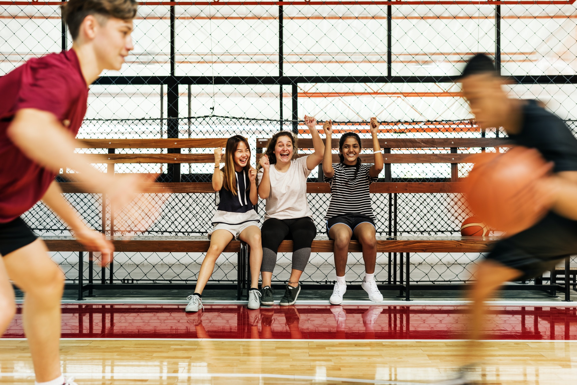 Teenage girls cheering the boys playing basketball